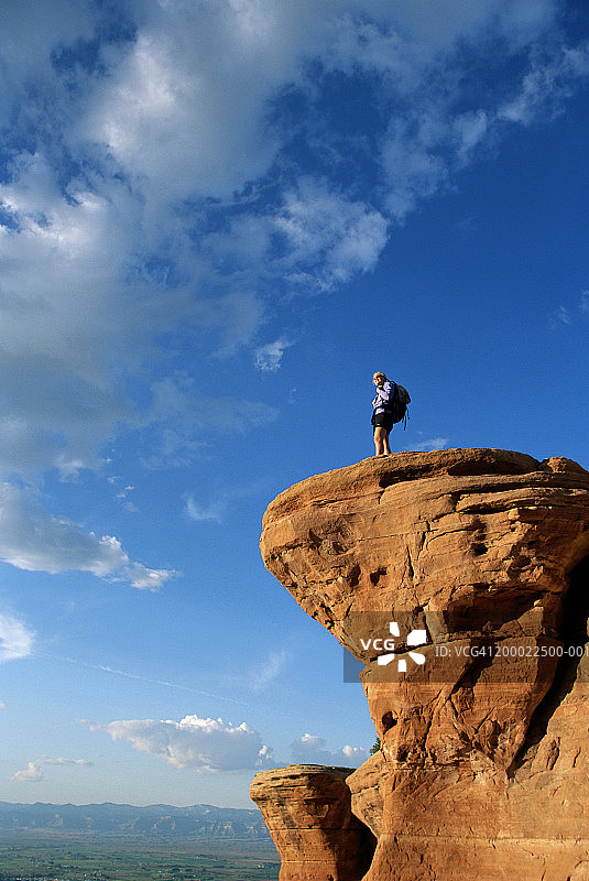 美国科罗拉多州，站在砂岩悬崖上的女徒步旅行者，低角度图片素材