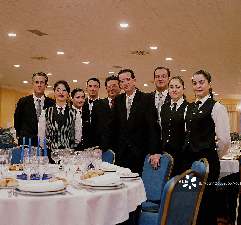 服务员和女服务员站在空餐桌旁，肖像图片素材