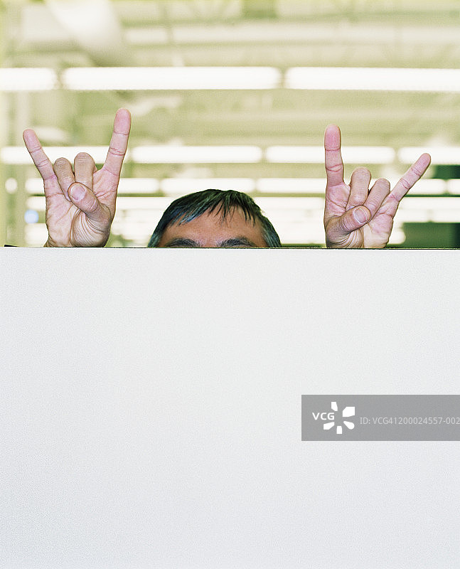 隔间墙后做手势的男人图片素材