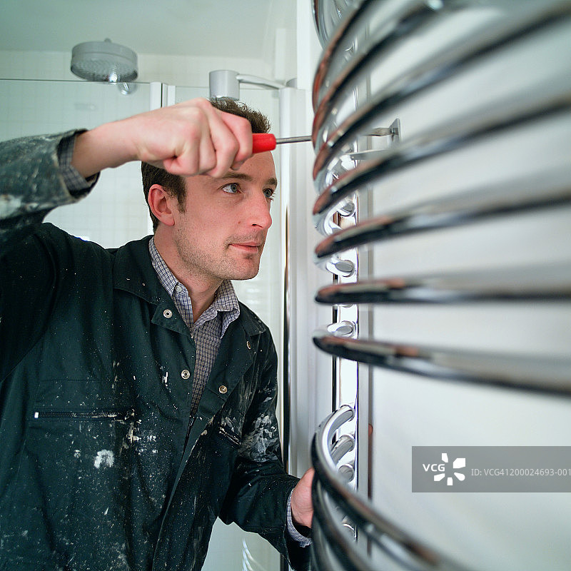 水管工将散热器拧到墙上图片素材