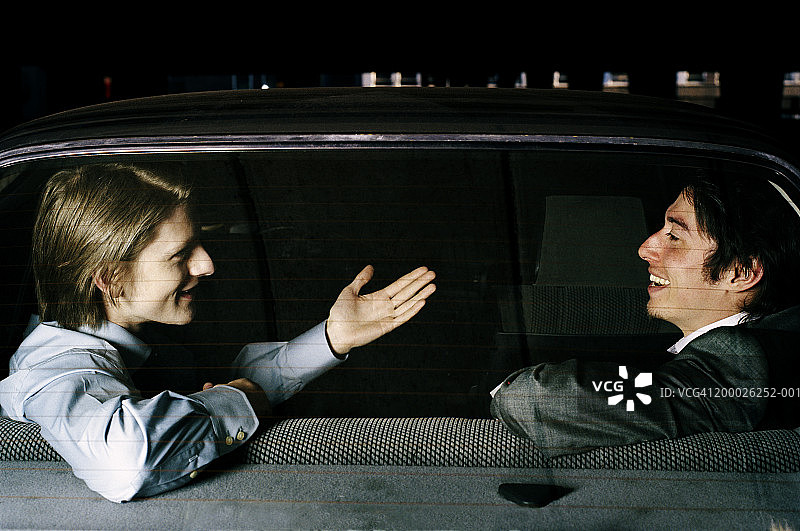 透过后挡风玻璃看车里的两个男人，其中一个在做手势图片素材