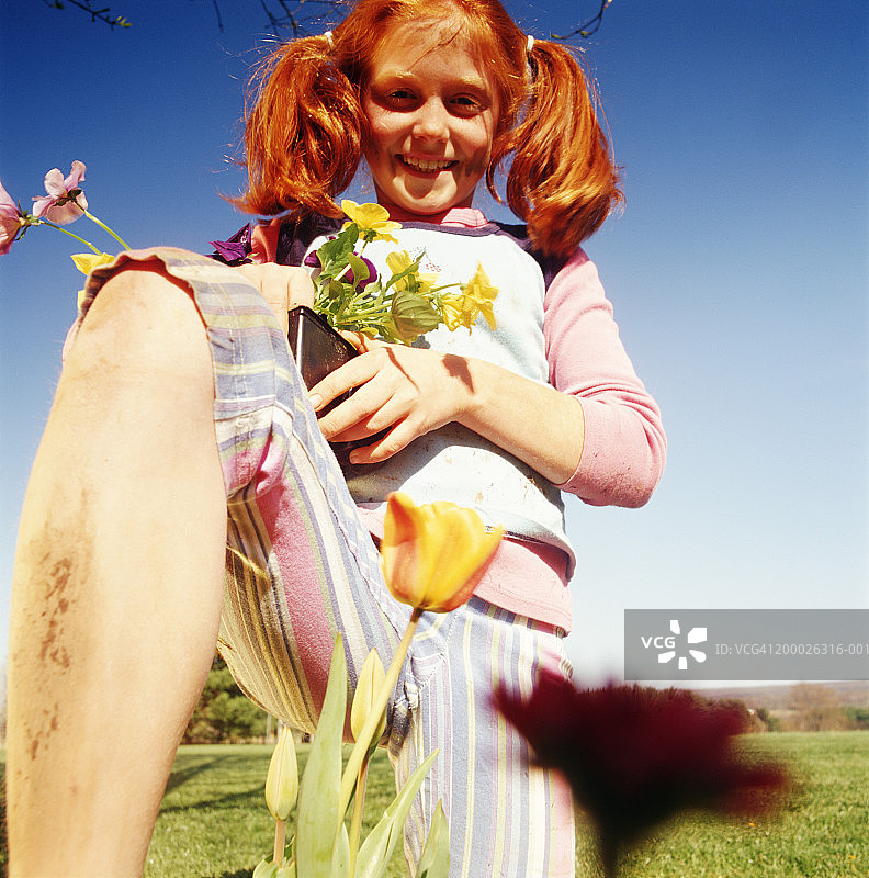 腿上沾着泥土，手捧鲜花的女孩（8-10岁）肖像图片素材