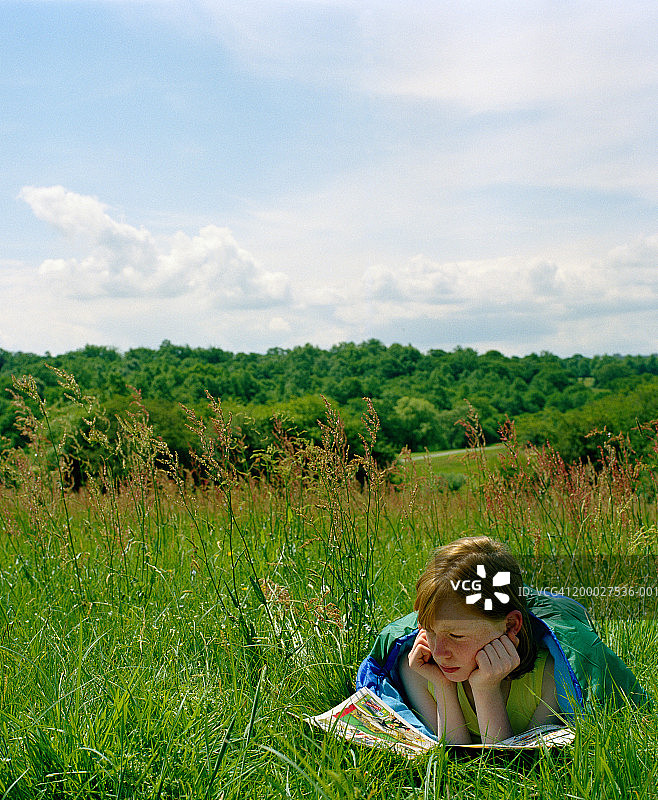 在田野里阅读漫画的女孩（9-11岁）图片素材