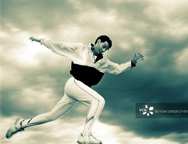 男人在户外进行跳跃跑步（棕褐色和蓝色调黑白照片）图片素材