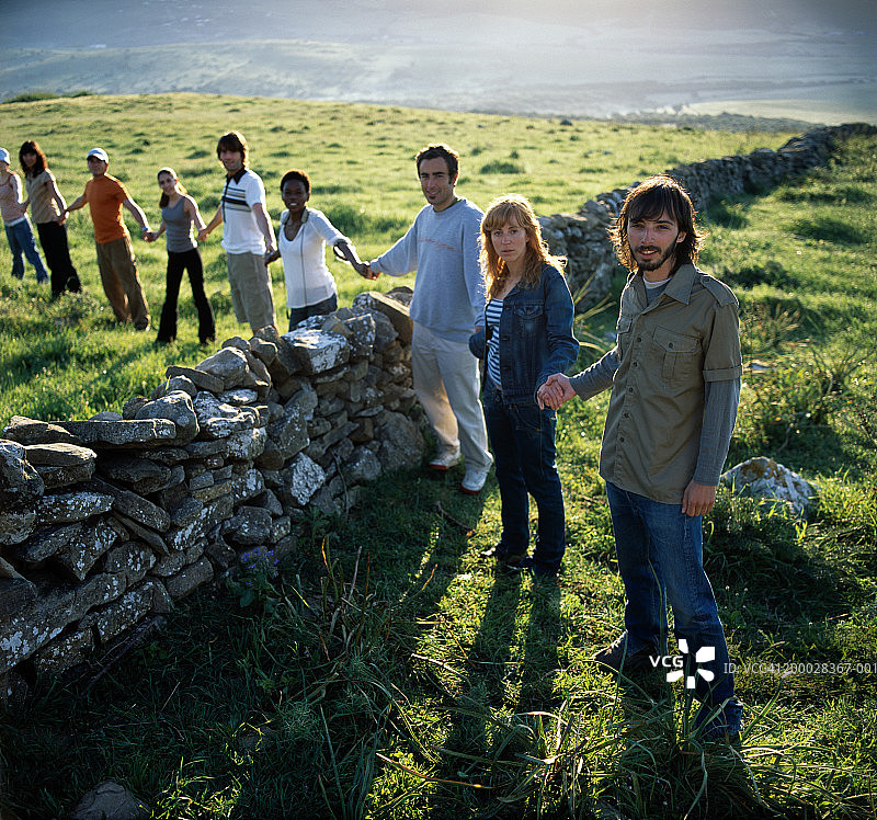 人们手牵手站在石头墙边图片素材