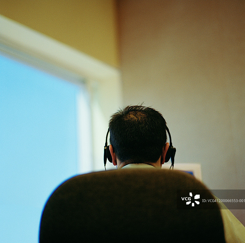 在办公室使用耳机的商人（背面视角）图片素材