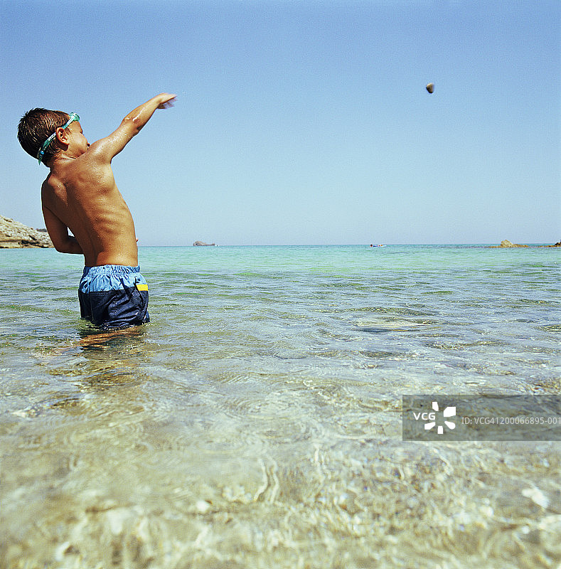 （6-8岁）男孩在海里扔鹅卵石图片素材