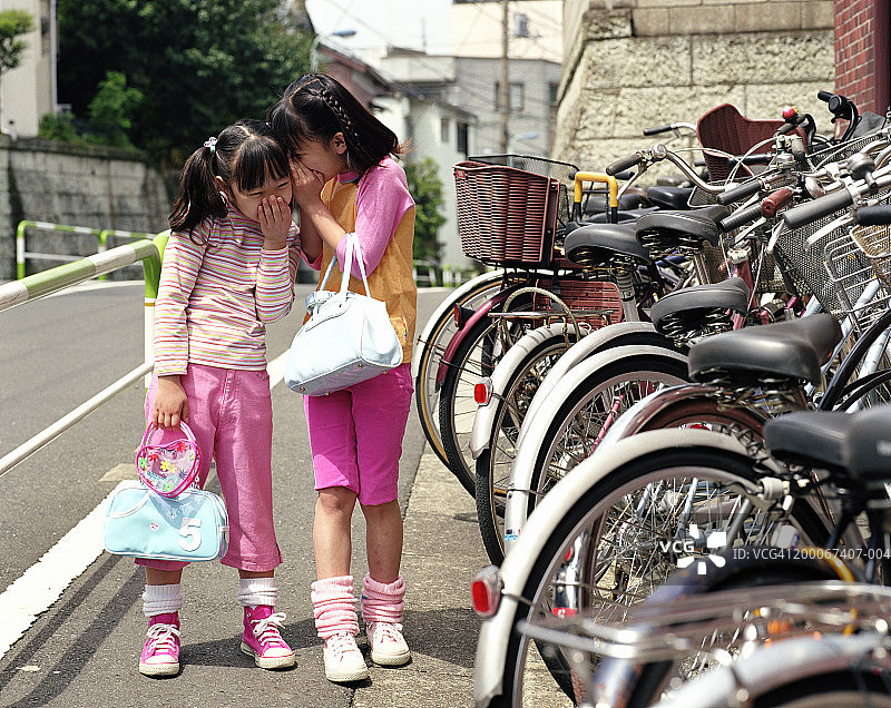 两女孩在自行车旁窃窃私语，欢笑图片素材