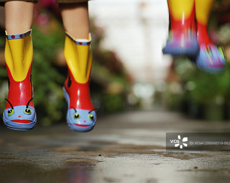 两个男孩（5-7岁）穿着橡胶靴跳跃，底部模糊图片素材