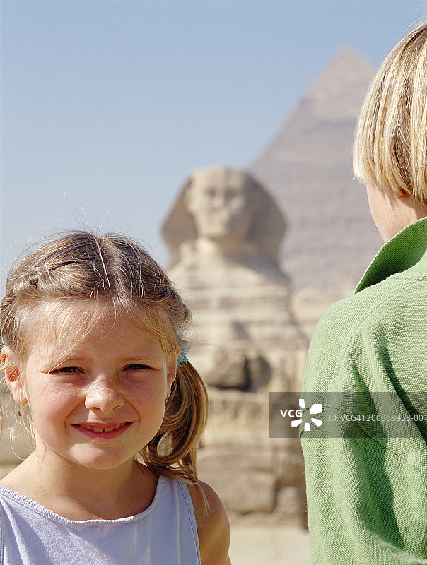 埃及吉萨：站在狮身人面像和金字塔前的女孩图片素材