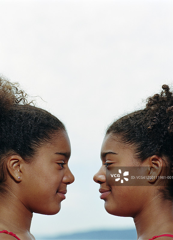 近距离面对面站立的双胞胎女孩（10-12岁）图片素材
