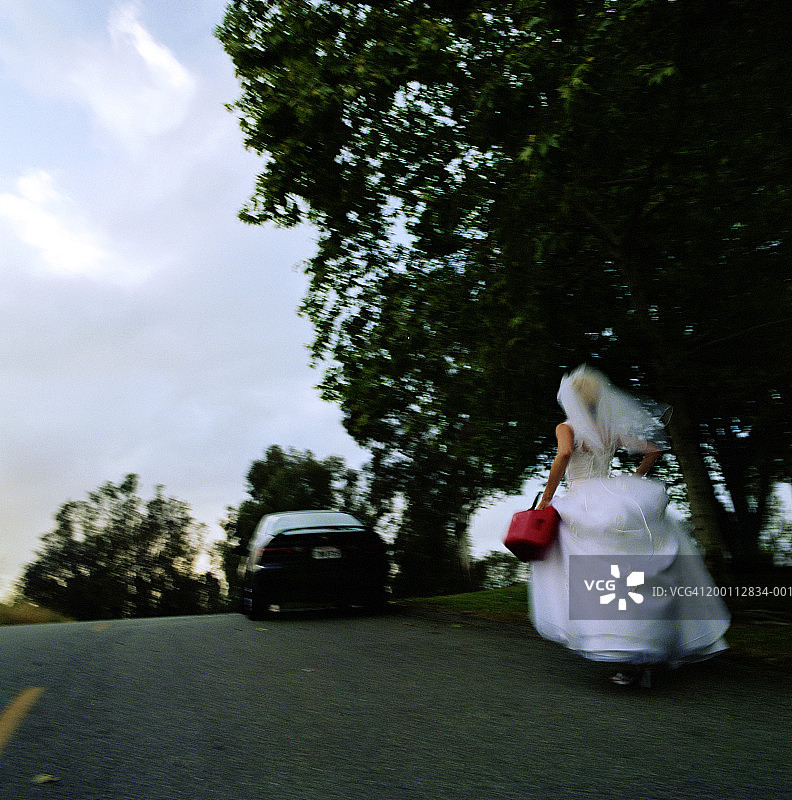 新娘拿着汽油桶跑向抛锚的汽车，后视图图片素材