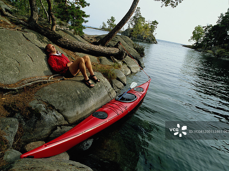 瑞典维特恩湖：男子在湖边皮划艇旁放松图片素材