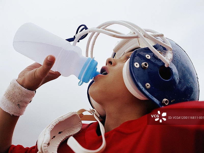 男孩（10-12岁）身穿橄榄球服，正在喝水，特写图片素材