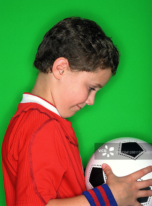 男孩站在绿色背景前拿着足球图片素材