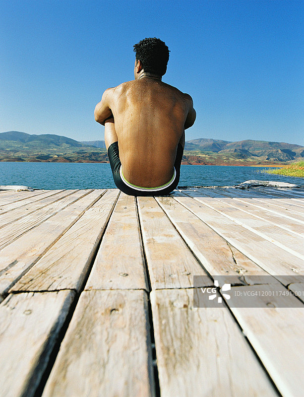男人坐在码头边，后视图图片素材