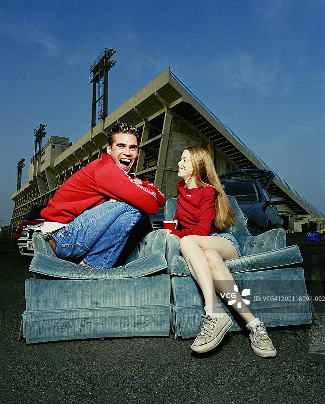 年轻情侣坐在体育场停车场躺椅上图片素材