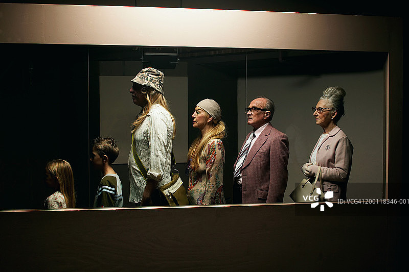 人们站在玻璃隔断后面排队图片素材