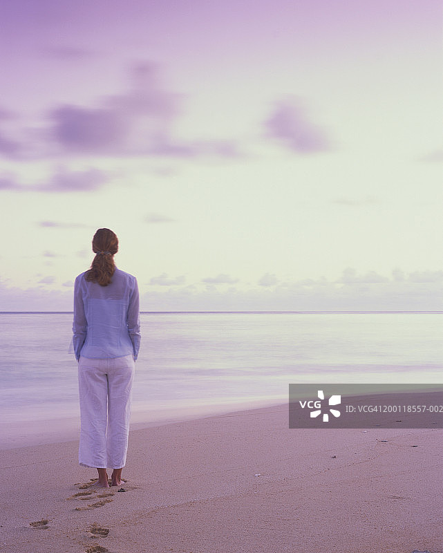 女人在海滩观看日出，后视图图片素材