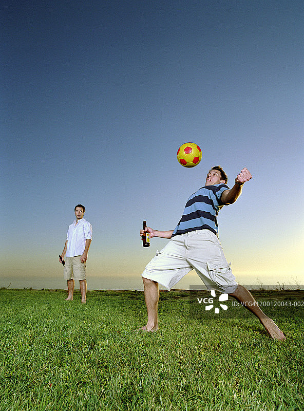 年轻男人踢足球，一人用胸部颠球图片素材