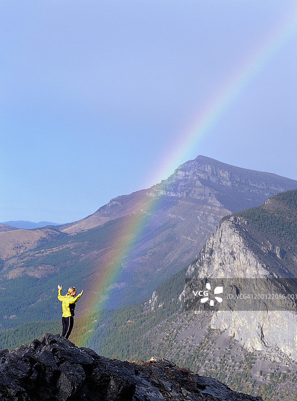 加拿大艾伯塔省亚姆努斯卡山峰上的女子与背景中的彩虹图片素材