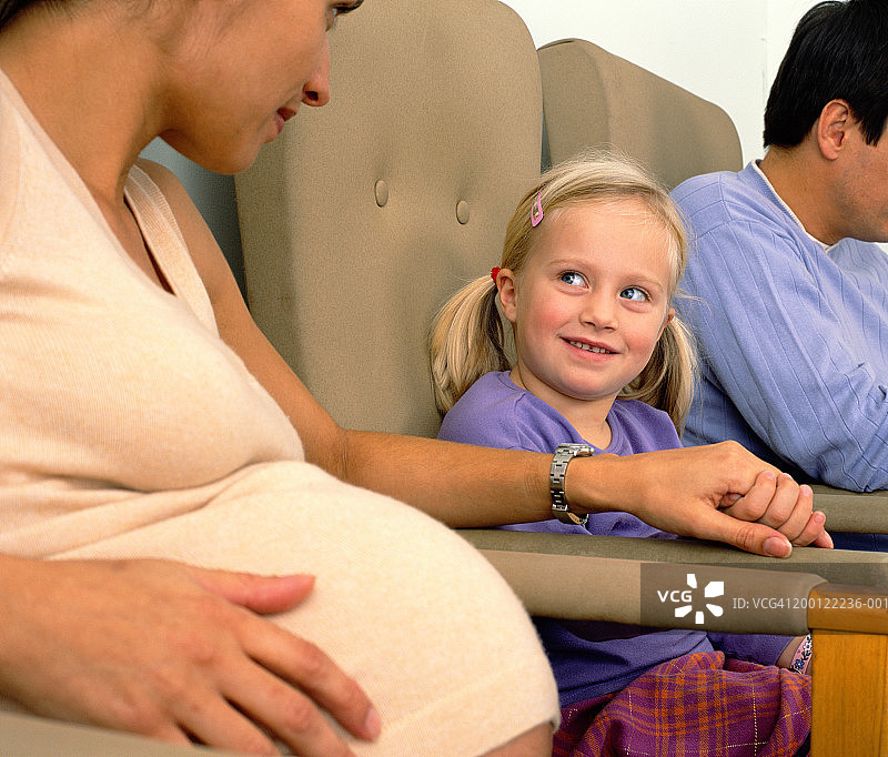 孕妇在等候室与小女孩(4-6岁)手牵手图片素材
