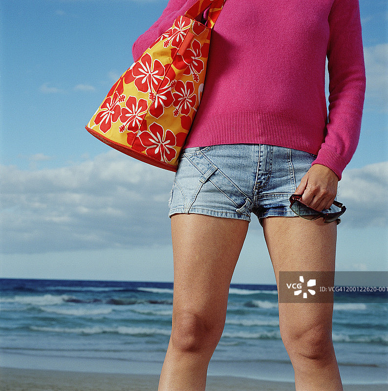 女人在海滩上拿着包和太阳镜（中部视角）图片素材