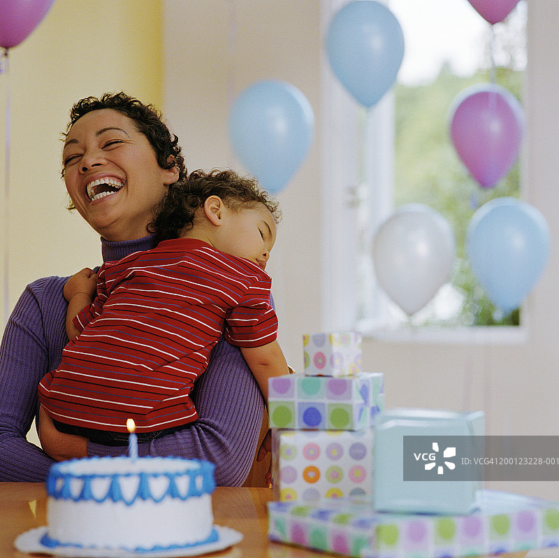 在生日派对上在母亲怀里睡着的男婴图片素材
