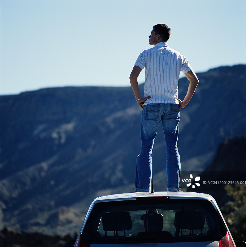 站在车顶上的年轻人，后视图图片素材