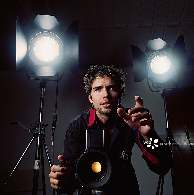 在工作室里手持快门线的摄影师图片素材