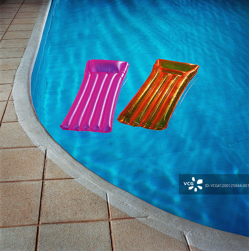 漂浮在游泳池中的两个充气床垫图片素材