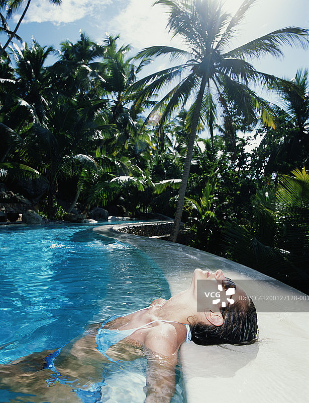 年轻女人在户外游泳池放松图片素材