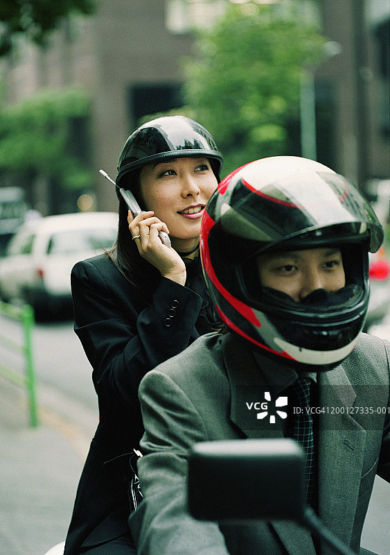 商务男女骑摩托车，女士在使用手机图片素材