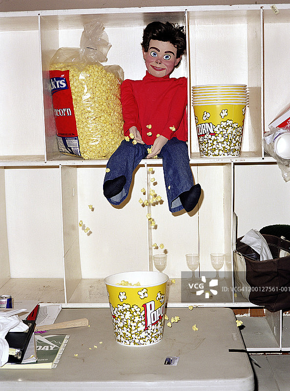 放在架子上与爆米花一起的腹语表演人偶图片素材