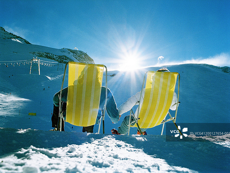 情侣在雪山坡上躺椅牵手（背影）图片素材