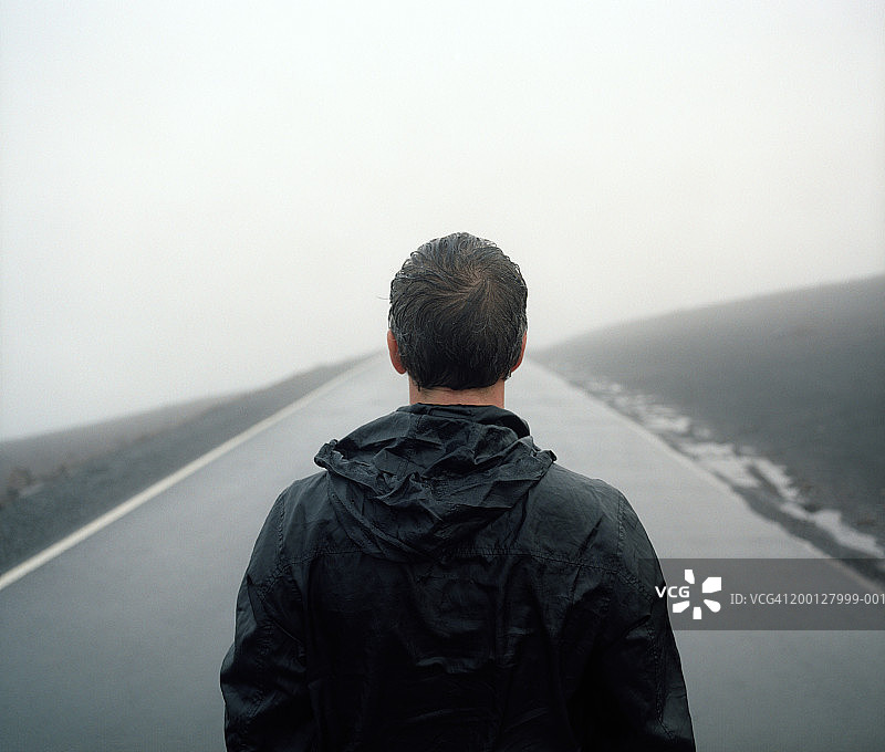 站在路中间的穿雨衣男人，后视图图片素材