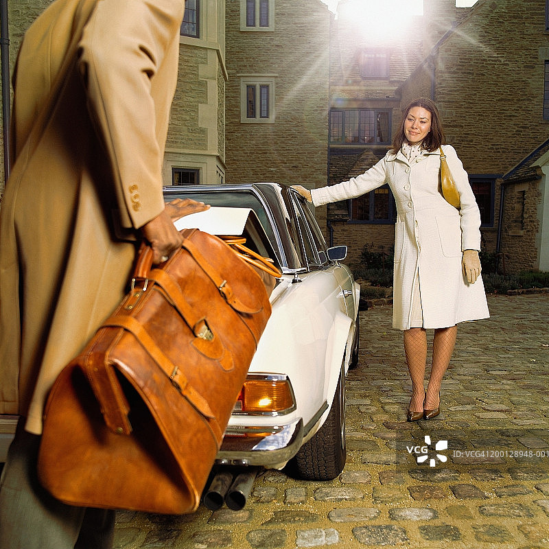 情侣在庭院里，男人从汽车后备箱里拿包图片素材