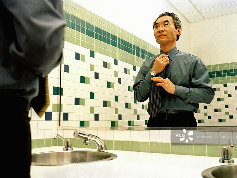 年长的男商人在浴室镜子里整理领带图片素材