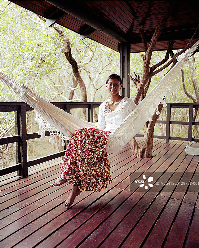 年轻女人坐在阳台的吊床上图片素材