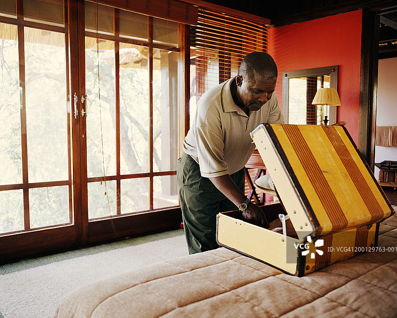 中年男人在床上打开行李箱图片素材