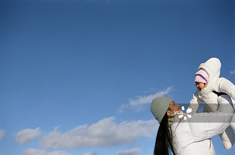 母亲在户外抱起女婴（6-9个月大）图片素材