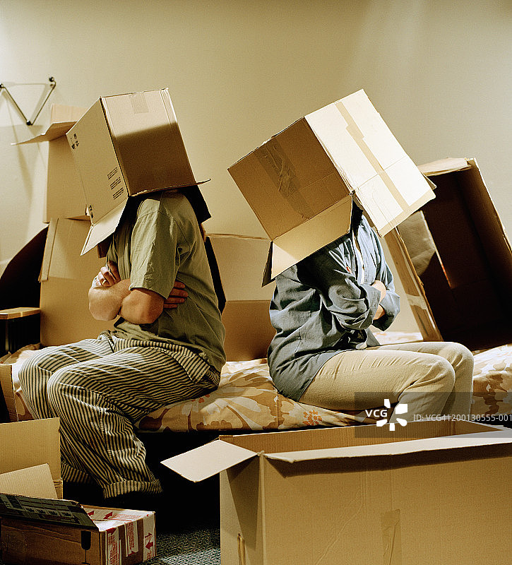 情侣背靠背坐在地上，头戴纸箱图片素材