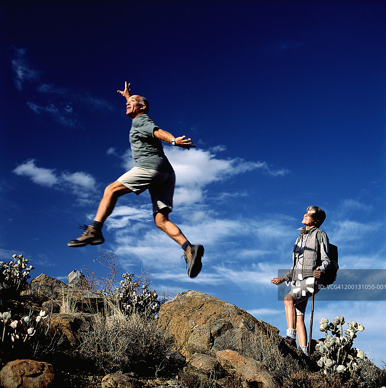 中年夫妇漫步，男人跳过岩石图片素材