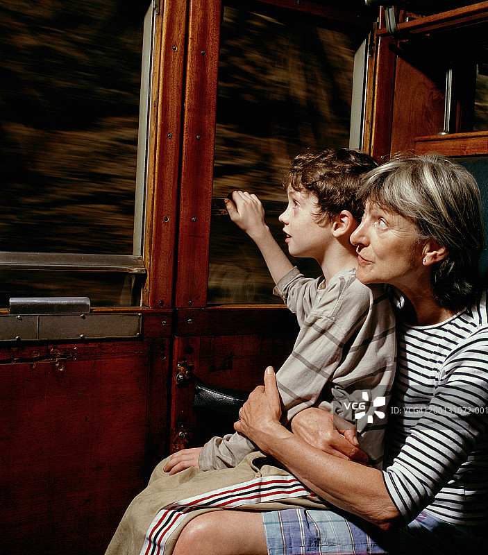 祖母和孙子(6-8岁)在火车窗口向外看图片素材