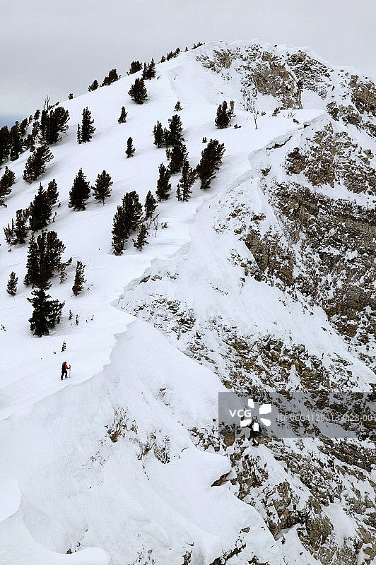 男人滑雪者在悬崖边徒步旅行，高角度视角图片素材