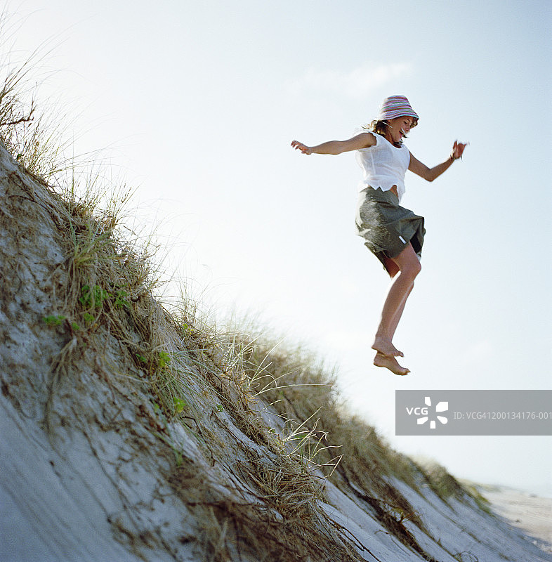 年轻女子跳下沙丘图片素材