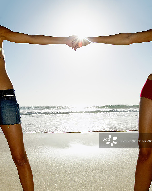 海滩上牵手的两位女性，镜头光晕图片素材