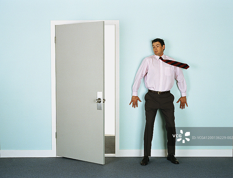 商务男士倚靠在门口的墙上，领带在风中飘扬图片素材