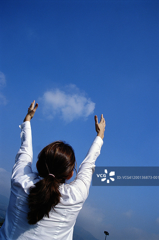 女人伸出手臂，仰望天空，背影图片素材