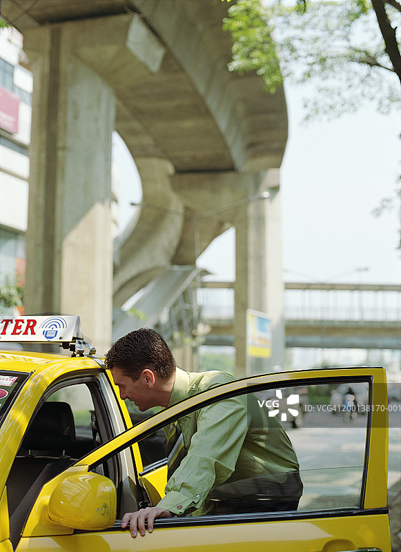 靠在出租车敞开的车门上的商人图片素材